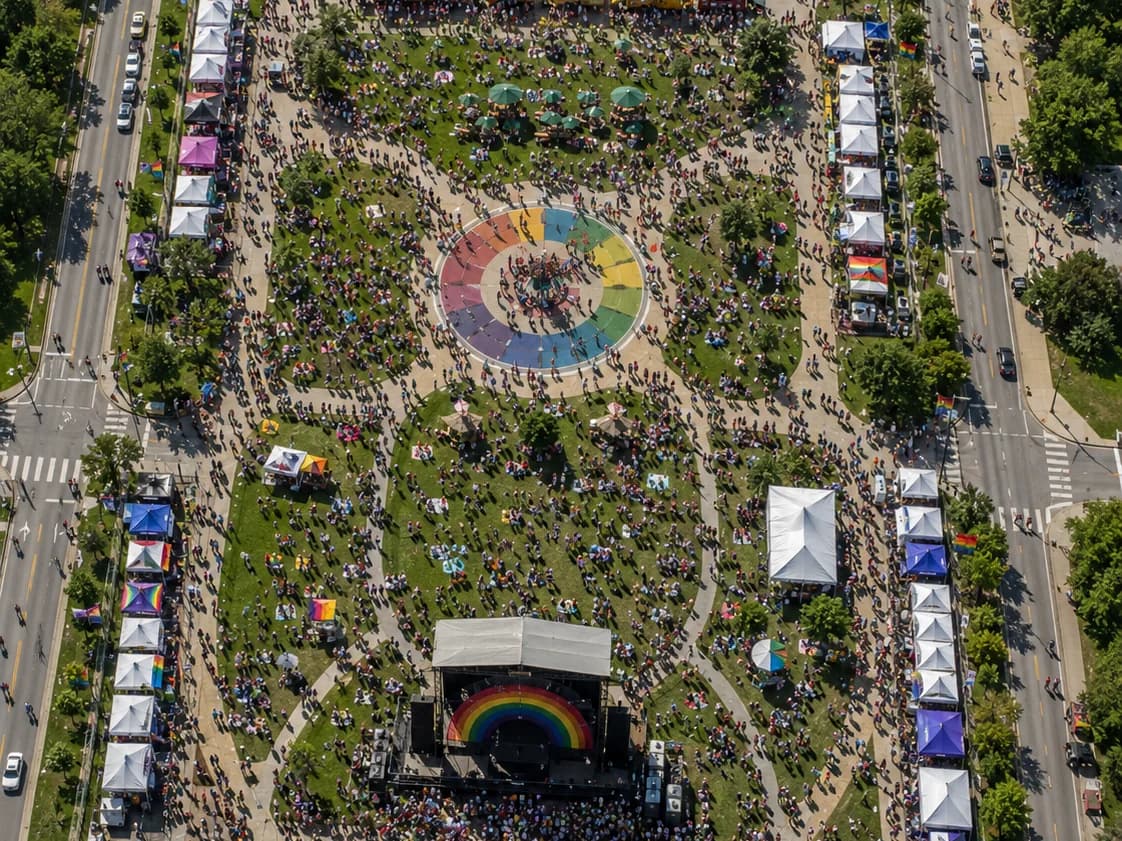 An aerial view of festival grounds with rows of white vendor tents, a stage, and the crowd between them